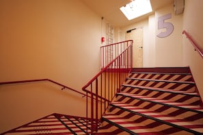 A staircase with red railings and striped carpet leading to a landing. - Hôtel EH OH Orly Rungis (Rungis)