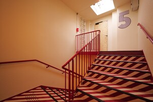 A staircase with red railings and striped carpet leading to a landing.