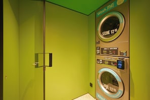 A laundry facility with two washing machines, each labeled for 12 kg capacity, and a dryer. - Hôtel EH OH Orly Rungis (Rungis)