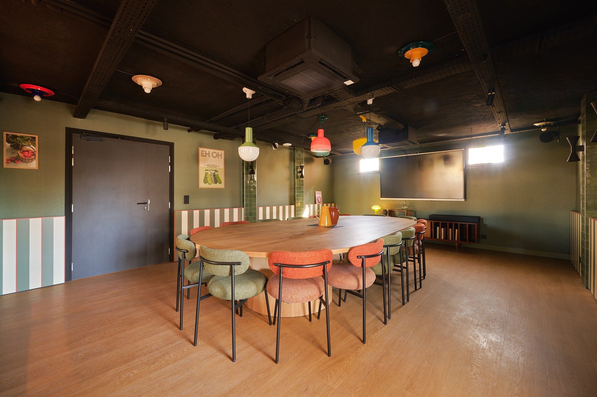 A conference room with a wooden table and chairs, a projector screen, and a large window.