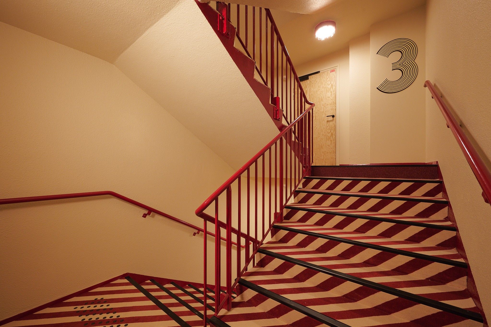 A staircase with red railings and a patterned carpet.