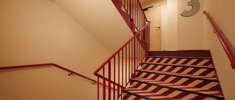 A staircase with red railings and a patterned carpet.