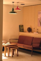 Una sala de estar acogedora con un sofá de madera, una mesita de madera y dos lámparas colgantes.
