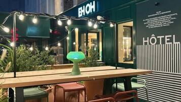 Un área de estar al aire libre con una mesa, sillas, luces colgantes y una lámpara verde.