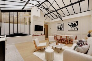 A modern living room with a glass ceiling, white furniture, and abstract art on the walls. - A Beaming 3-BR/2Ba - Montorgueil (Paris)