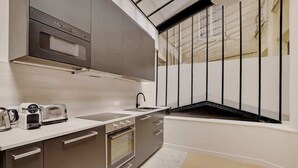 Eine moderne Küche mit Edelstahlgeräten, einem eingebauten Backofen und einem Fenster mit schwarzen Geländern.
