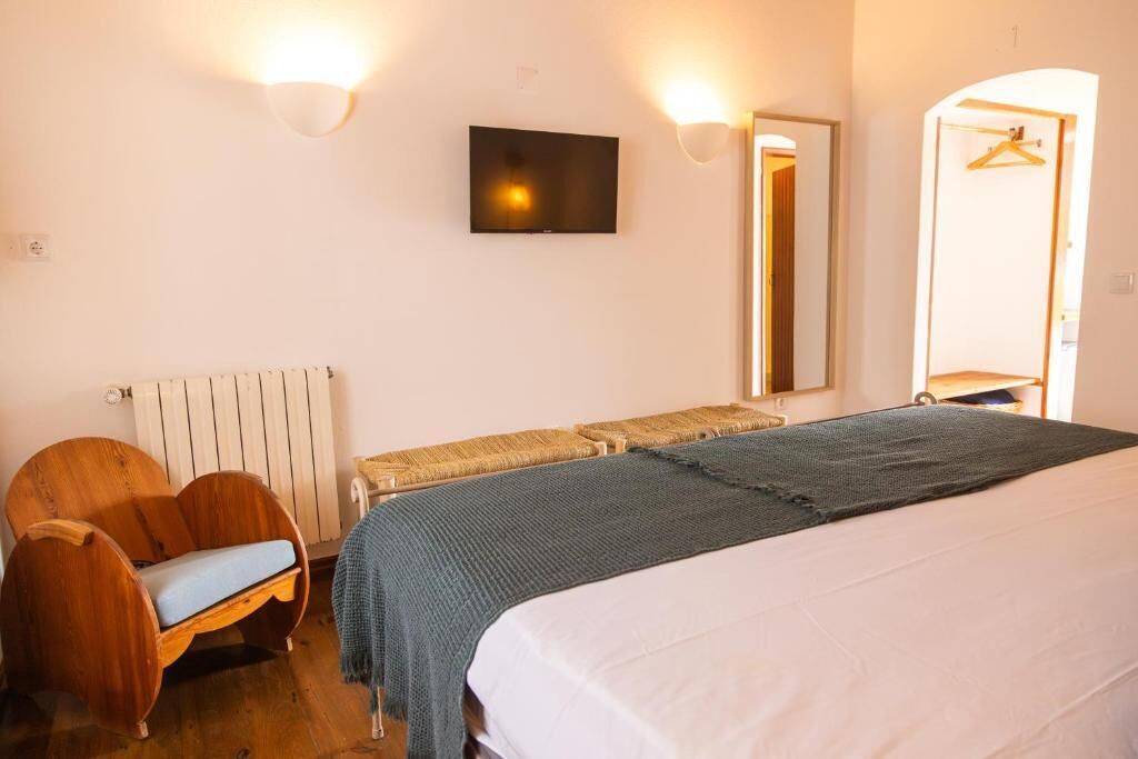 Ein Zimmer mit einem Bett, einem Sessel, einem Fernseher und einem Spiegel.