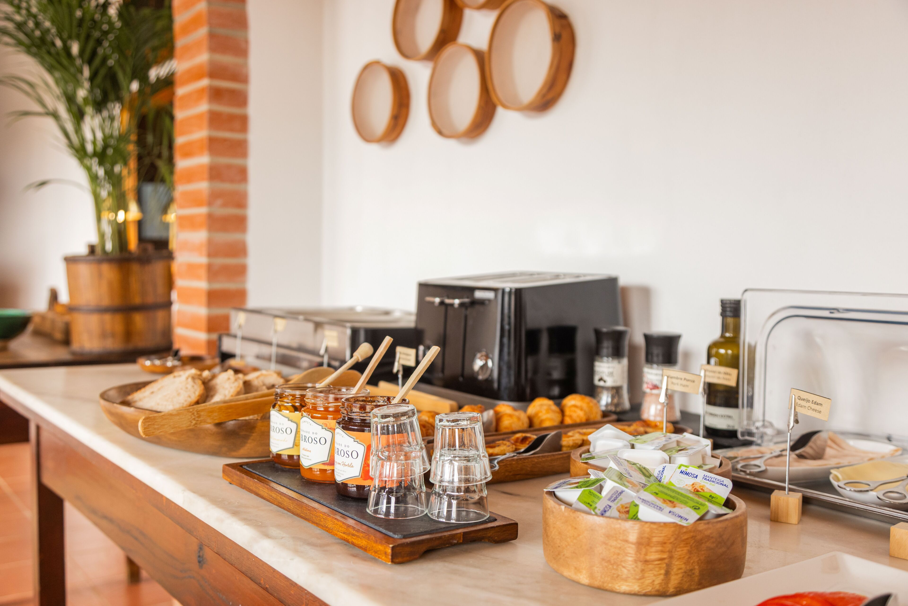 A breakfast buffet with bread, pastries, honey jars, and coffee-making equipment.