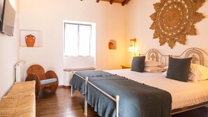 Un dormitorio con cama, escritorio, silla, televisor y un adorno en la pared.