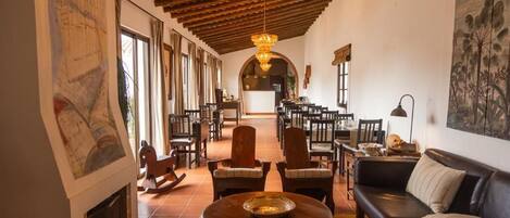 Un vestíbulo amplio con chimenea, techo de madera y un área de comedor al fondo.