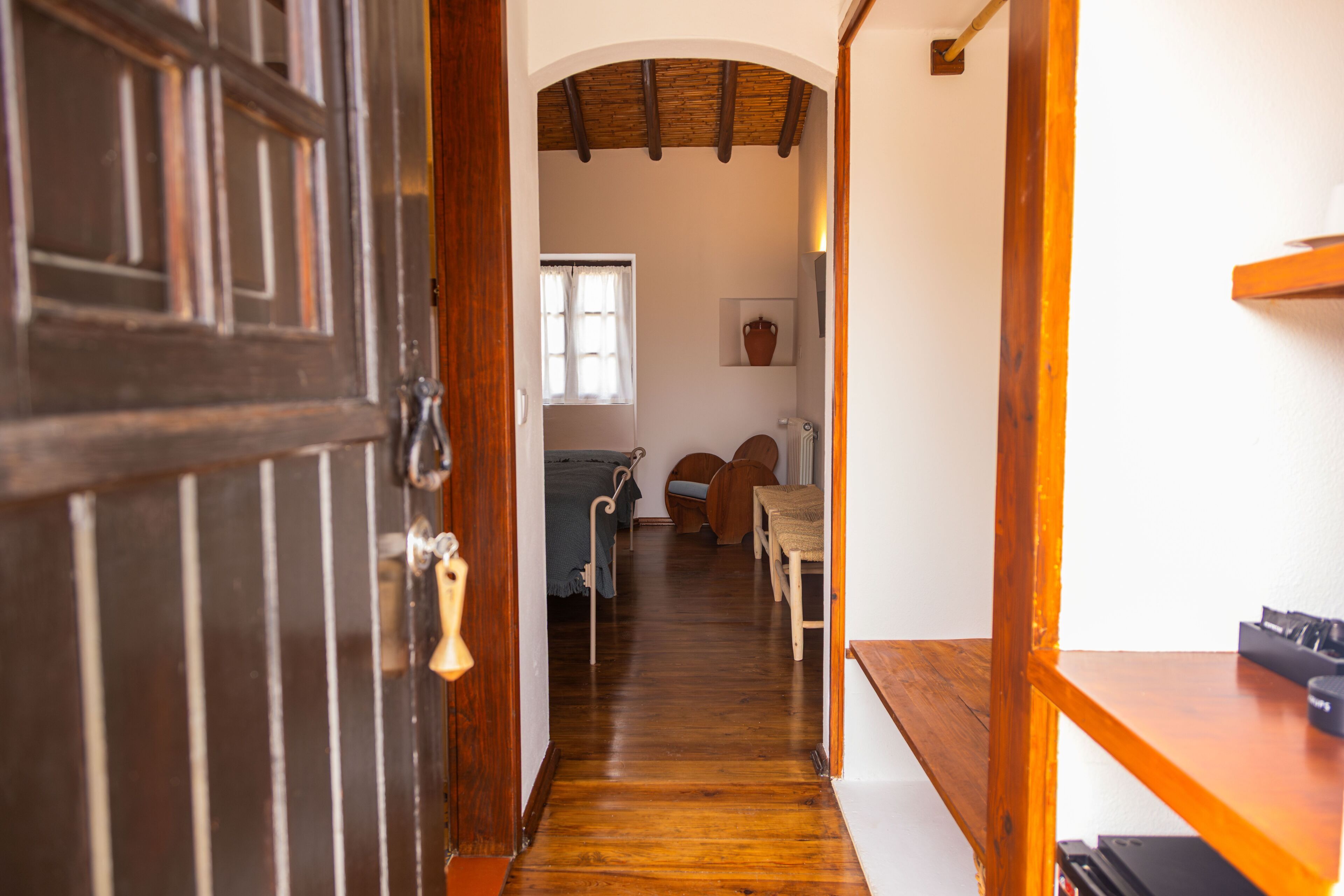 A wooden interior hallway with a door, a window, a radiator, and a shelf with items.