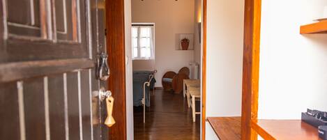 A wooden interior hallway with a door, a window, a radiator, and a shelf with items.