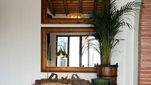 Una consola de madera con un espejo encima, una planta en maceta y una cesta tejida.