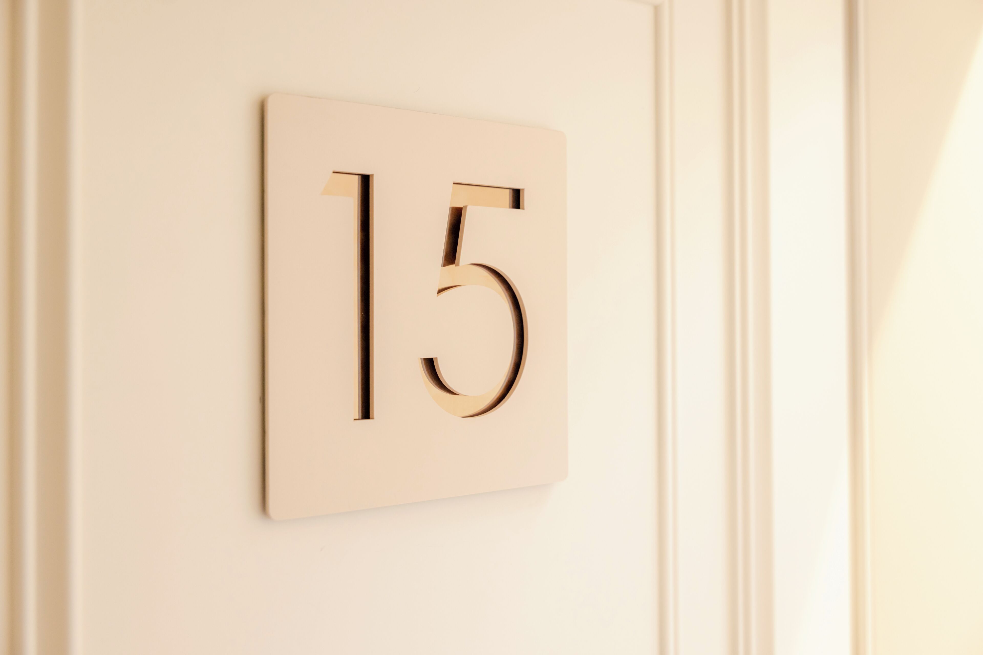 A wall-mounted number plate with the number 15.