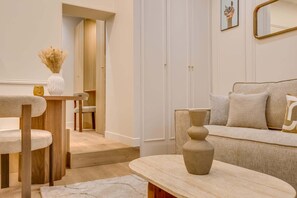 Ein modernes Wohnzimmer mit einer Couch, einem Couchtisch, einem Sessel und einer Vase mit Trockenblumen.