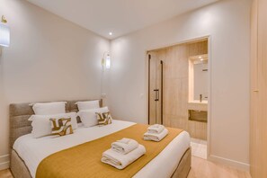 Ein Hotelzimmer mit Bett, einem Holzschrank, einem Spiegel und einem durch die Schranktüren einsehbaren Badezimmer.