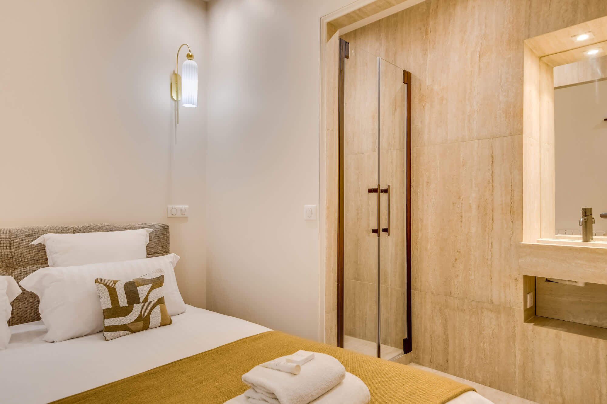 A hotel room with a bed, a shower, and a bathroom vanity.