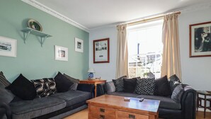 Un salon avec deux canapés gris, une table basse en bois et une fenêtre avec des rideaux.