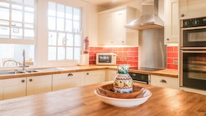 Une cuisine moderne avec un plan de travail en bois, des appareils électroménagers en acier inoxydable et une grande fenêtre.