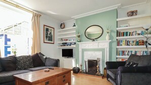 Un salon avec une cheminée, des étagères à livres, un canapé et une table basse.