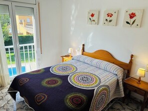 A bedroom with a bed, a nightstand, a lamp, and a view of a pool. - SAONA VILLAS (VN BALI 8): villa for 6 people, private pool, wifi, air conditioning (Les Tres Cales)