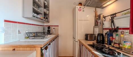 A compact kitchen with a built-in oven, a coffee maker, and a gas stove.