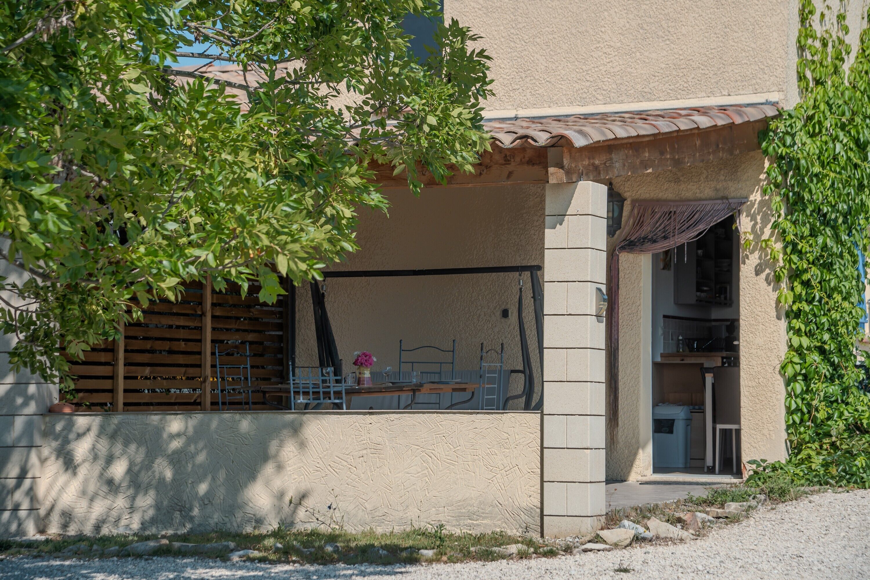 A building with a covered outdoor seating area, a window with a view, and a door leading to an interior space.