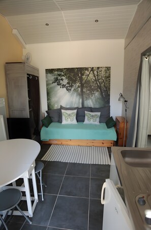 A compact room with a bed, a small table, and a chair. There is a large window on one side and a door leading to another room. - Apartment with Private Terrace and Pool (Mévouillon)