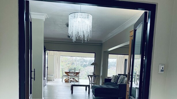 An open doorway leading to a living area with a chandelier, a sofa, and a view of the outdoors. - Selborne Golf Estate Villa P15 (Pennington)