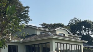 A two-story house with a covered patio, large windows, and a brick foundation. - Selborne Golf Estate Villa P15 (Pennington)