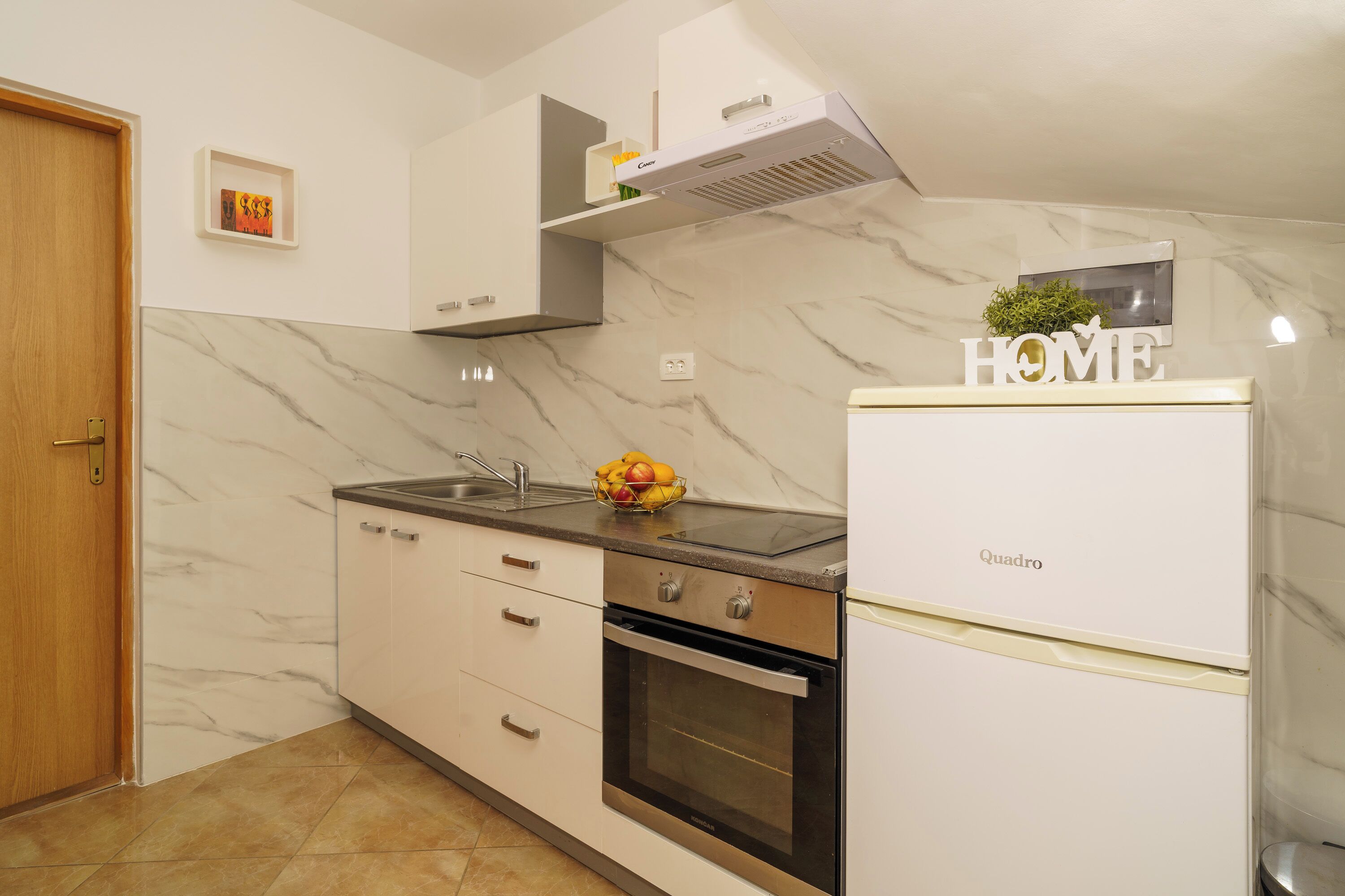 A kitchen with a built-in oven, a refrigerator, and a sink.