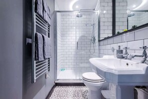 A modern bathroom with a glass-enclosed shower, a white toilet, and a sink with a mirror above it. - Modern 2-Bed Flat in Central Leeds - Sleeps 6 (Leeds)