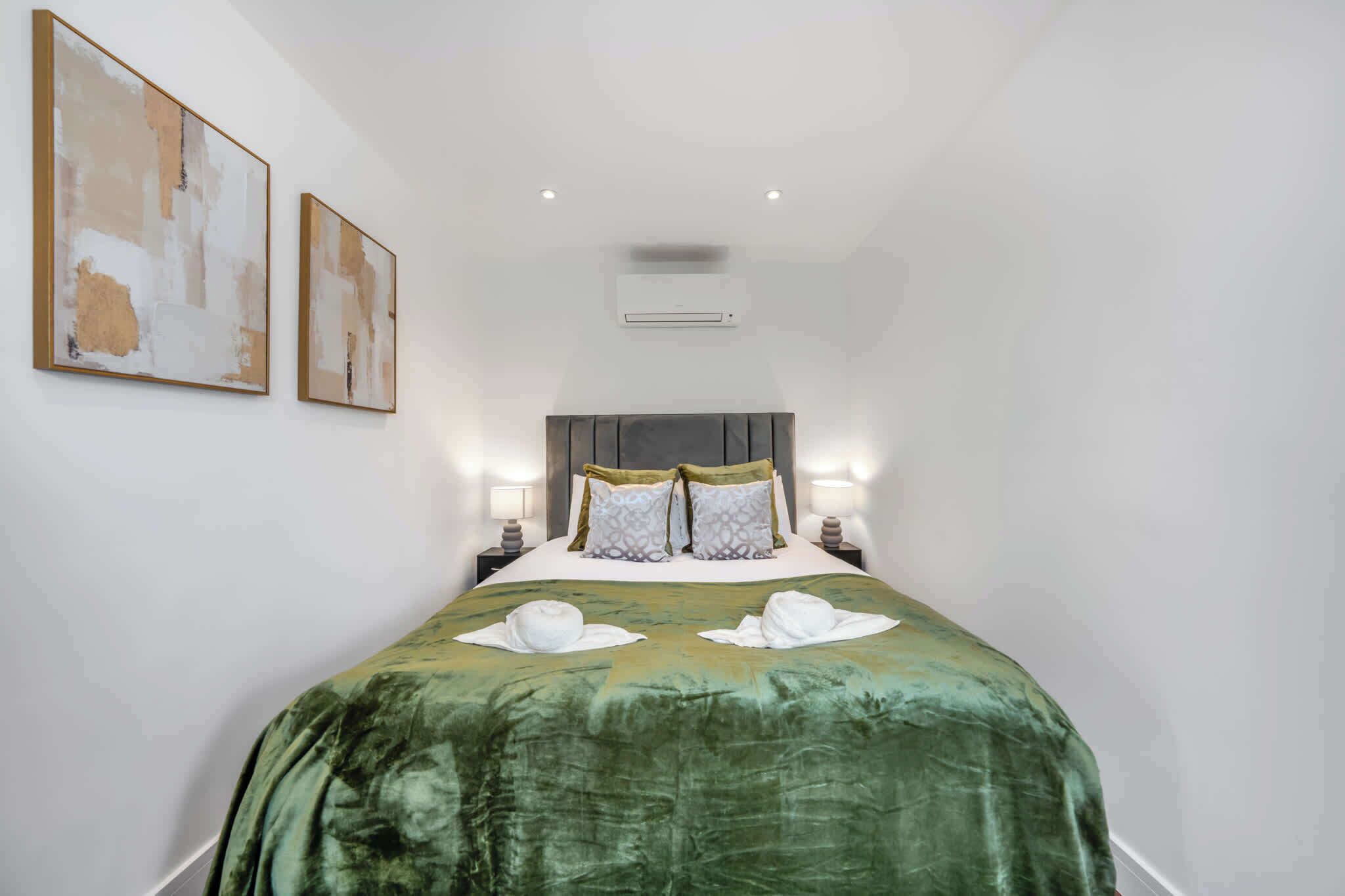 Hotelkamer met een groot bed, twee nachtkastjes met lampen, een hoofdeinde en twee abstracte schilderijen aan de muur.