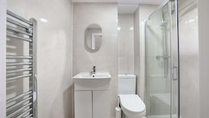 A modern bathroom with a glass shower enclosure, a white sink, and a toilet. - Standard Studio in Knightsbridge (London)