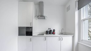 A compact kitchen with a microwave, coffee maker, and sink. - Charming One Bedroom Flat in Knightsbridge (London)