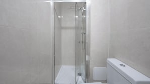 A modern bathroom with a glass-enclosed shower, a white toilet, and a white sink. - Charming One Bedroom Flat in Knightsbridge (London)