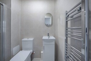Een badkamer met toilet, wastafel, spiegel en handdoekhouder.