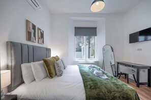 Una camera d'albergo moderna con un letto, una scrivania, una sedia, una televisione e una finestra con vista.