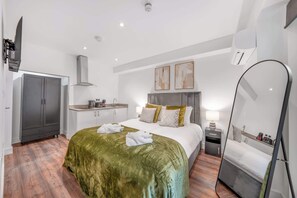 Ein modernes Hotelzimmer mit Bett, Schreibtisch, Kleiderschrank und Spiegel.