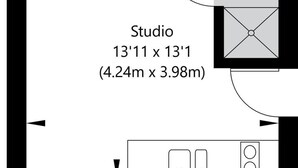 Een studio-appartement met een kitchenette, badkamer en een klein zithoekje.