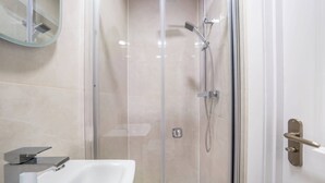 Een moderne badkamer met een douchecabine van glas, een wit wastafelmeubel en een spiegel.
