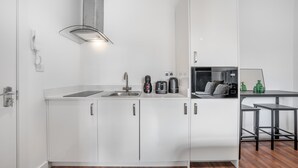 Een moderne keuken met witte kasten, een roestvrijstalen afzuigkap, een spoelbak, een koffiezetapparaat en een magnetron.