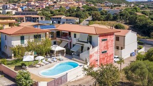 Ein Wohngebäude mit Swimmingpool, mehreren Balkonen und Blick auf eine Hügelstadt.