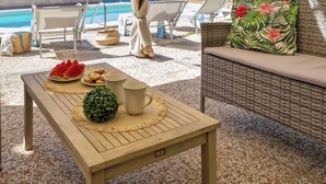 Ein Holztisch mit Unterlage, einer kleinen grünen Pflanze, einem Teller mit Wassermelonenstücken und zwei Tassen.