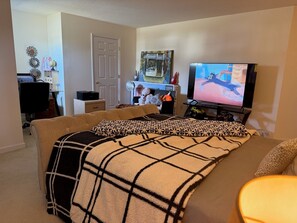 Un salon confortable avec une grande télévision, un canapé et une table basse.