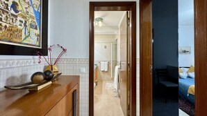 En hotellkorridor med en träbeklädd receptionsdisk, en inramad karta och en liten inblick i ett badrum och ett sovrum.