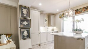 Una cocina con armarios blancos, piso de espiga y una lámpara colgante.