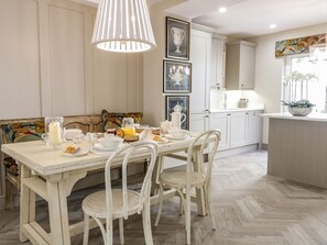 Ein Essbereich mit einem für das Frühstück gedeckten Tisch, einer Bank und einer Küche im Hintergrund.