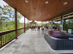 Un espace extérieur abrité comprenant un jacuzzi, des sièges et une vue sur le paysage environnant.