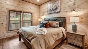 Ein Schlafzimmer einer Holzhütte mit einem Bett, Nachttischen und einem Deckenventilator.